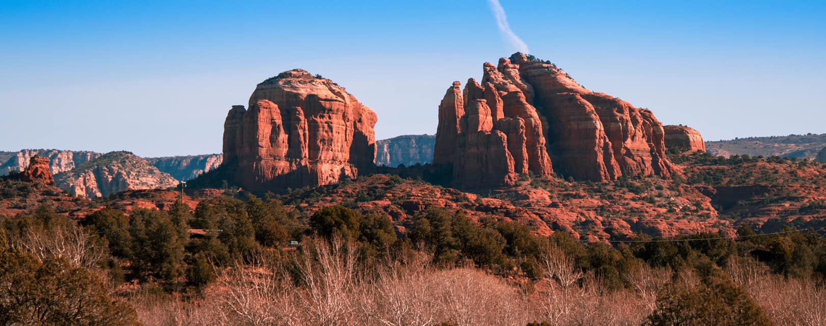 View of the red rock formations at Cathedral Rock in Sedona, Arizona, captured on a clear day with vivid blue skies and scenic desert landscape.