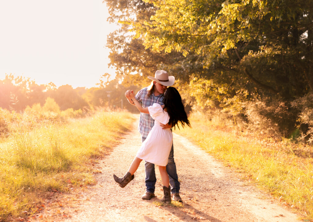 Couple kissing on a sunlit country road at golden hour, illustrating how to plan an elopement with a romantic, rustic, and intimate vibe.
