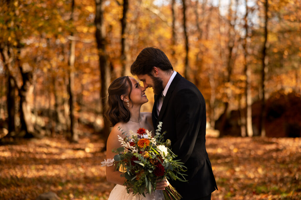 Bride and groom standing close together during a fall elopement in an Illinois forest surrounded by autumn leaves