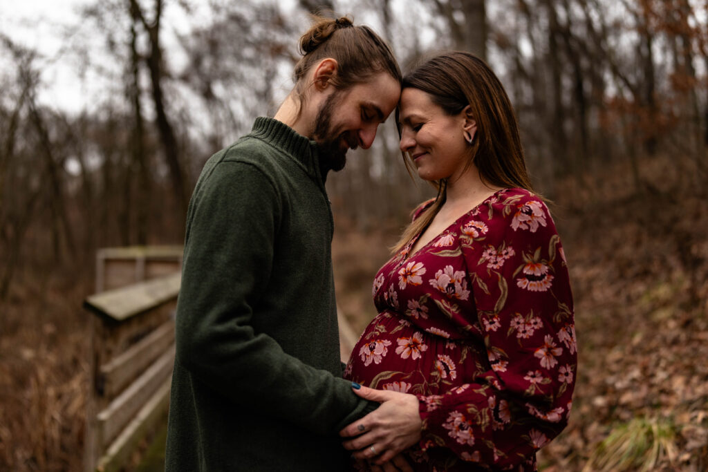 Couple sharing an intimate moment during a maternity session in an Illinois forest in late fall