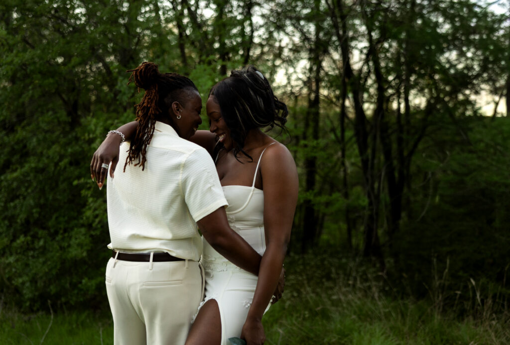 Couple embracing in a grassy wooded area at River Legacy Park in Arlington, Texas